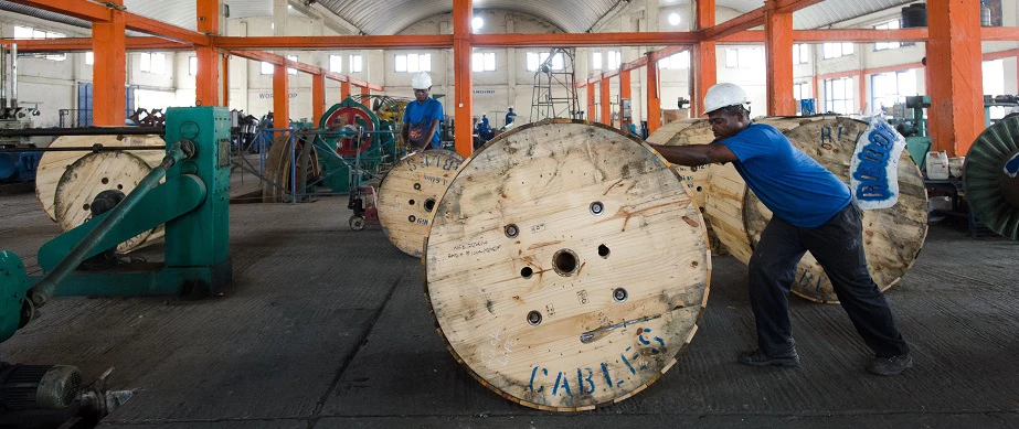 A worker rolling a spool of cable across the factory floor at Reroy Cables, an IFC beneficiary in Tema, Ghana. © Nyani Quarmyne, Panos/IFC